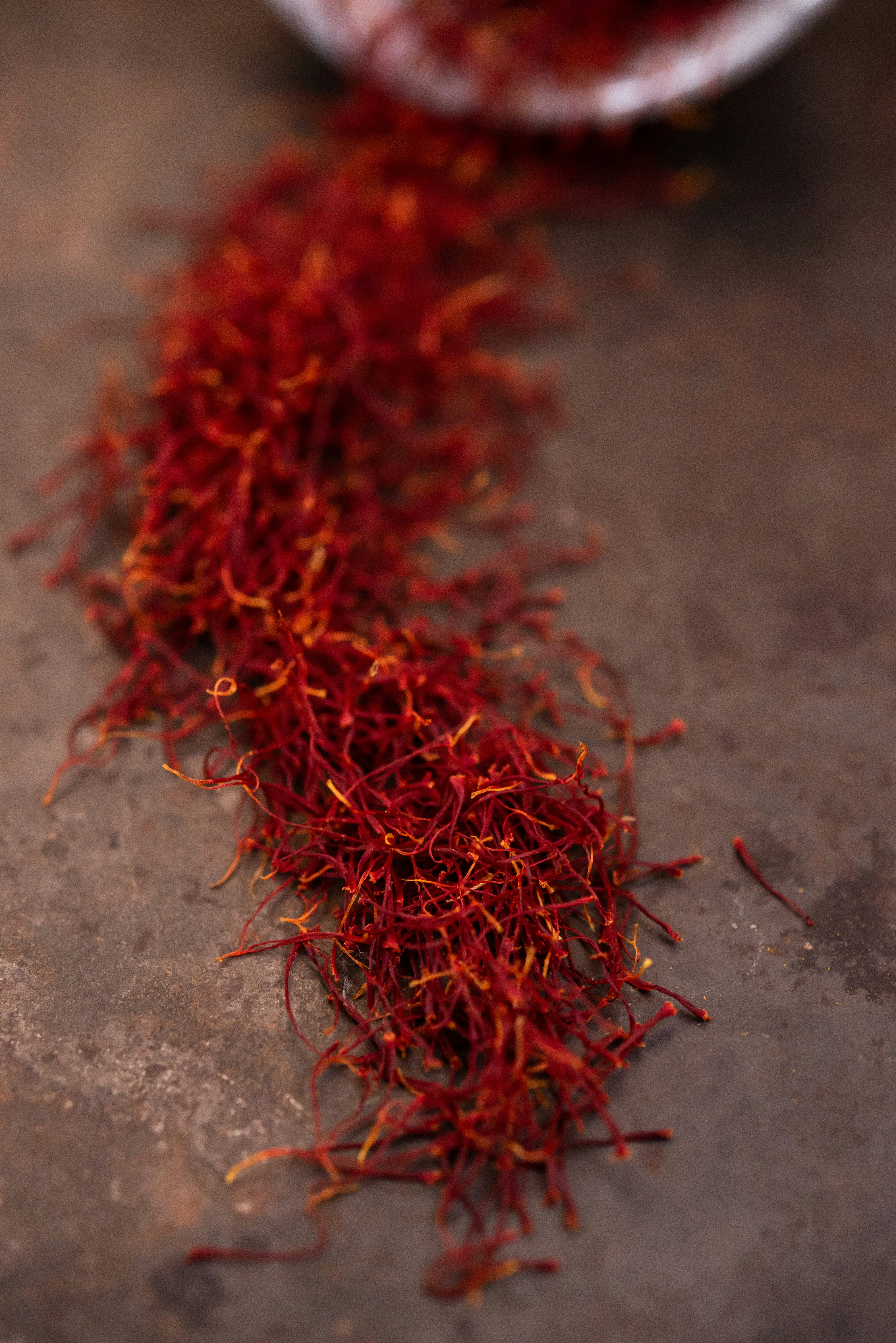 Saffron threads trailing from a bowl on dark stone